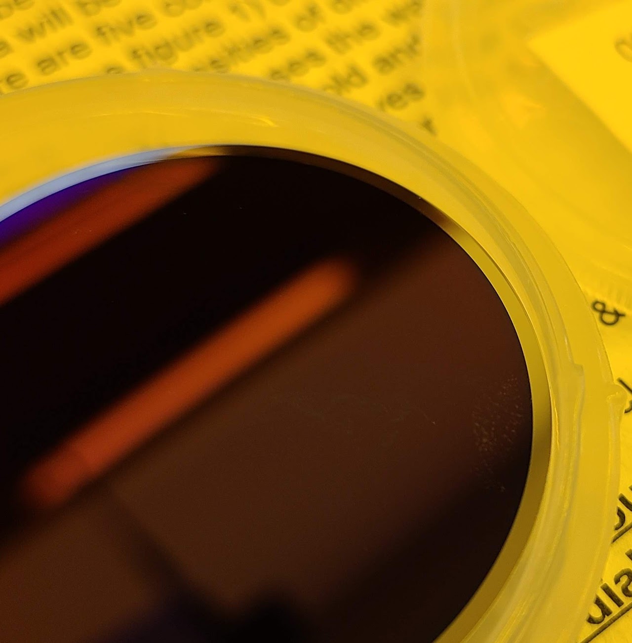Closeup of a germanium wafer in a plastic case. This wafer has been coated with an SiO anti-reflective coating, which is why reflections from the ceiling lights appear darker.